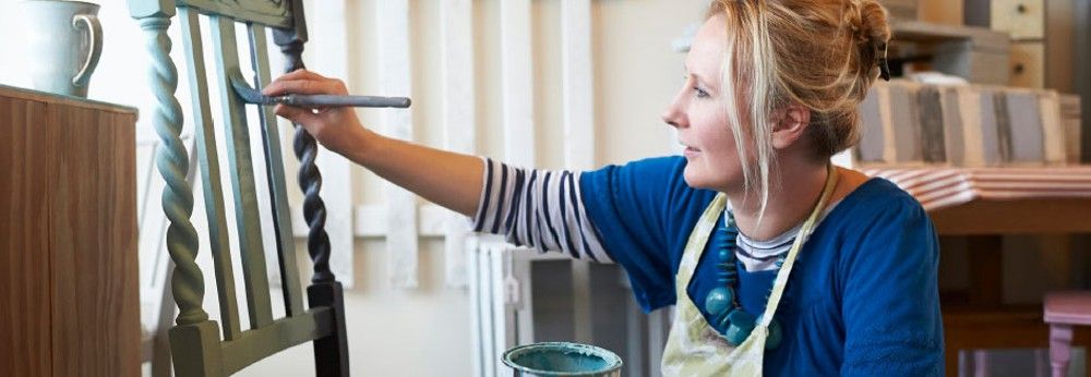 Person streicht einen Stuhl